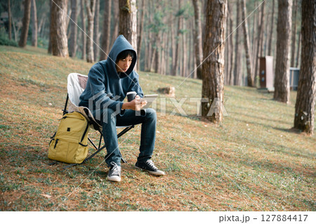 Remote work technology online close up communication smart phone laptop telephone digital travel brown nature sunlight camp beverage morning sit drink coffee tent orange outlying concept background. 127884417