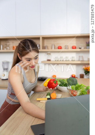 Wellness and Healthy Living. Young woman preparing fresh vegetables in a modern kitchen. 127885479