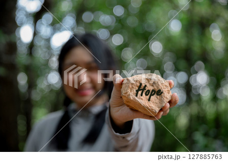 Woman hand holding stone with word hope engraved concept for faith, love, spirituality, religion. Happy female being thankful. Spiritual girl praying with hope. Positive asian young woman feeling hope Woman hand holding stone with word hope engraved concept for faith, love, spirituality, religion. Happy female being thankful. Spiritual girl praying with hope. Positive asian young woman feeling hope 127885763