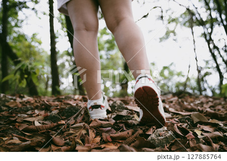 Hiking action on mountain grass trail path. Close up of female hiker shoe. adventurous lifestyle of hiker and backpack to travel and trek mountain, enjoy every walk and hike part of thrilling journey 127885764