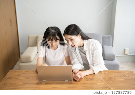 ノートパソコンを使う母娘 127887780