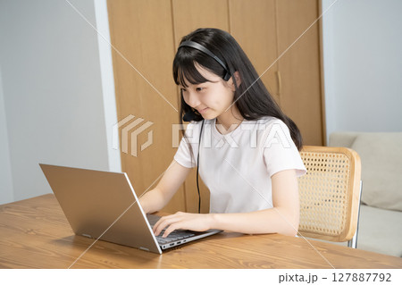 ヘッドセットをつけてパソコンの操作をする女の子 127887792