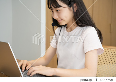 ヘッドセットをつけてパソコンの操作をする女の子 ヘッドセットをつけてパソコンの操作をする女の子 127887796