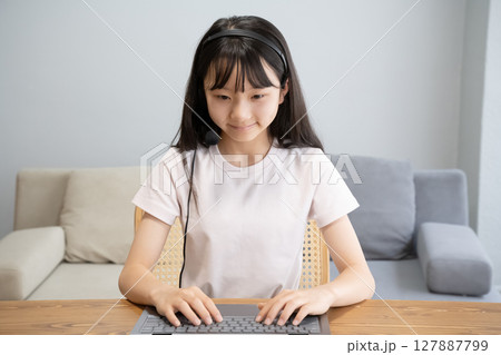 ヘッドセットをつけてパソコンの操作をする女の子 ヘッドセットをつけてパソコンの操作をする女の子 127887799