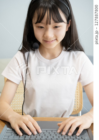ヘッドセットをつけてパソコンの操作をする女の子 127887800
