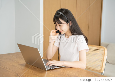 ヘッドセットをつけてパソコンの操作をする女の子 127887807