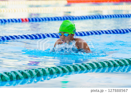 Swimmer child swims breaststroke swimming style in a race swimming pool. Water sports and competition, learning to swim classes for children. Swimmer child swims breaststroke swimming style in a race swimming pool. Water sports and competition, learning to swim classes for children. 127888567