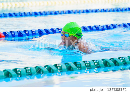 Swimmer child swims breaststroke swimming style in a race swimming pool. Water sports and competition, learning to swim classes for children. Swimmer child swims breaststroke swimming style in a race swimming pool. Water sports and competition, learning to swim classes for children. 127888572