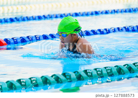 Swimmer child swims breaststroke swimming style in a race swimming pool. Water sports and competition, learning to swim classes for children. Swimmer child swims breaststroke swimming style in a race swimming pool. Water sports and competition, learning to swim classes for children. 127888573