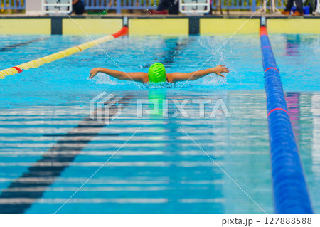 Swimmer child swims butterfly swimming style in a race swimming pool. Water sports and competition, learning to swim classes for children. Swimmer child swims butterfly swimming style in a race swimming pool. Water sports and competition, learning to swim classes for children. 127888588