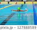 Swimmer child swims butterfly swimming style in a race swimming pool. Water sports and competition, learning to swim classes for children. 127888589