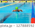 Swimmer child swims butterfly swimming style in a race swimming pool. Water sports and competition, learning to swim classes for children. 127888592