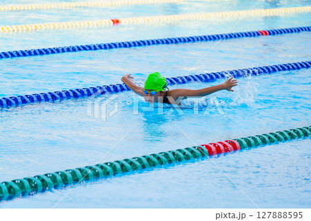 Swimmer child swims butterfly swimming style in a race swimming pool. Water sports and competition, learning to swim classes for children. 127888595