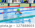 Swimmer child swims breaststroke swimming style in a race swimming pool. Water sports and competition, learning to swim classes for children. 127888603