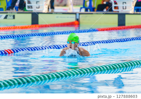 Swimmer child swims breaststroke swimming style in a race swimming pool. Water sports and competition, learning to swim classes for children. Swimmer child swims breaststroke swimming style in a race swimming pool. Water sports and competition, learning to swim classes for children. 127888603