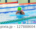 Swimmer child swims breaststroke swimming style in a race swimming pool. Water sports and competition, learning to swim classes for children. 127888604