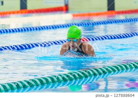 Swimmer child swims breaststroke swimming style in a race swimming pool. Water sports and competition, learning to swim classes for children. Swimmer child swims breaststroke swimming style in a race swimming pool. Water sports and competition, learning to swim classes for children. 127888604