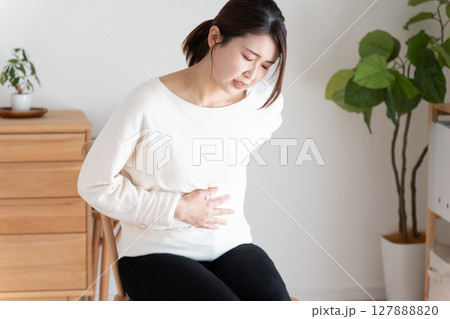 お腹と背中を押さえる体調不良の女性 お腹と背中を押さえる体調不良の女性 127888820