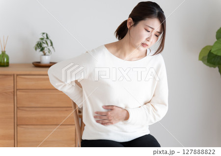 お腹と背中を押さえる体調不良の女性 127888822