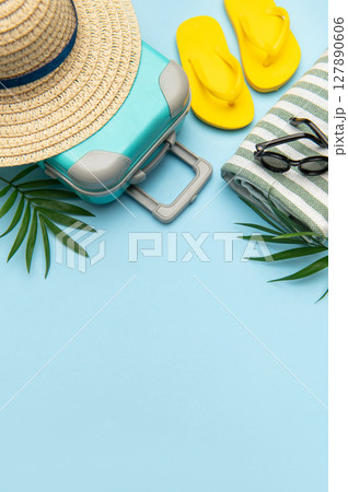 Suitcase, beach towel, flip flops, sunglasses and a straw hat suggesting summer vacation travel Suitcase, beach towel, flip flops, sunglasses and a straw hat suggesting summer vacation travel 127890606