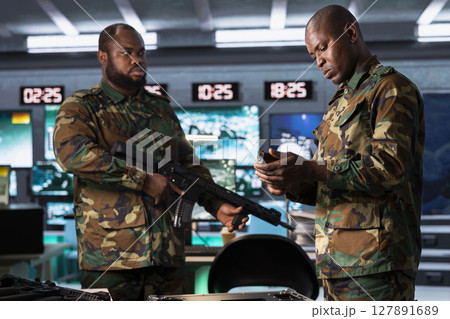Military officers checking weapons in control room, ensuring bullets and supplies are properly and evenly distributed. Army soldiers managing combat load equipment before warfare assault mission 127891689
