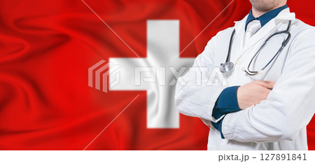 Switzerland healthcare concept. Male doctor on Switzerland flag. Doctor with crossed arms on Switzerland flag 127891841