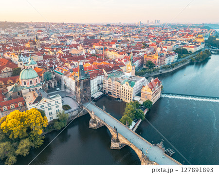 The stunning Charles Bridge stretches across the Vltava River, connecting historic sites in Prague. Old Town Bridge Tower rises majestically, complementing the scenic urban landscape at sunset. 127891893