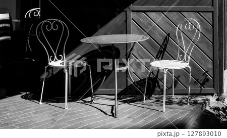 Vintage Wrought Iron Bistro Table and Chairs in Dramatic Shadow 127893010