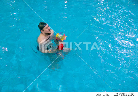 Dad and child are swimming indoor pool. Father teachs to swim. Dad and child are swimming indoor pool. Father teachs to swim. 127893210