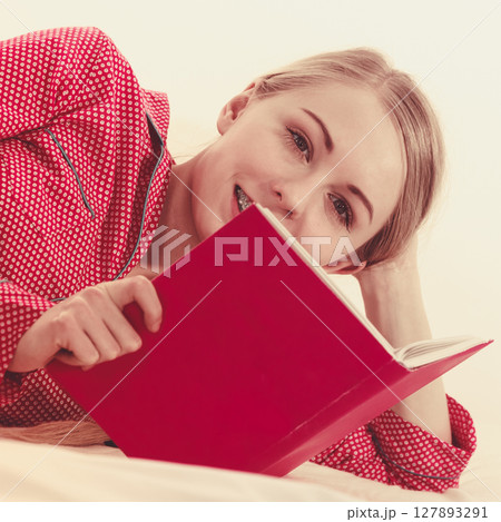 Woman relaxing in bed reading book Woman relaxing in bed reading book 127893291