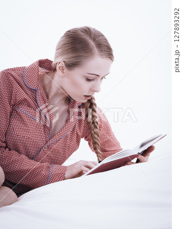 Woman relaxing in bed reading book 127893292