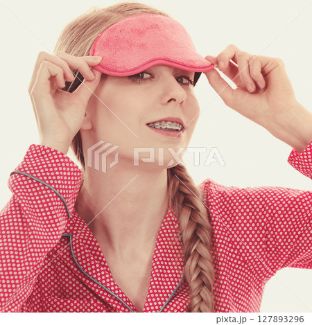 Sleepy woman wearing pink eye band 127893296
