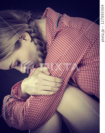 Sad depressed girl sitting huddled 127893304