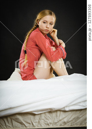 Sad depressed young woman in bed 127893308