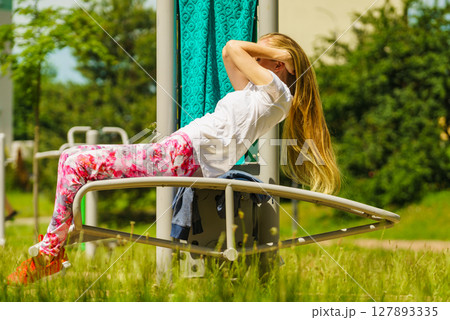 Girl doing situps in outdoor gym 127893335