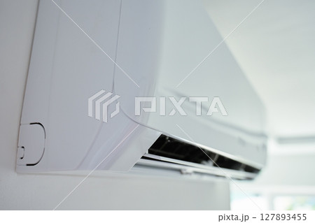 Modern wall mounted air conditioner unit in white room. Home climate control Modern wall mounted air conditioner unit in white room. Home climate control 127893455