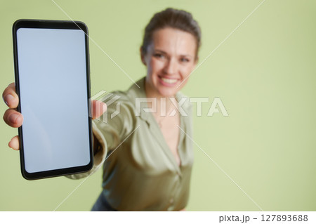 Smiling woman presenting smartphone screen 127893688