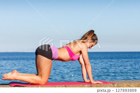 Woman doing sports exercises outdoors by seaside 127893809