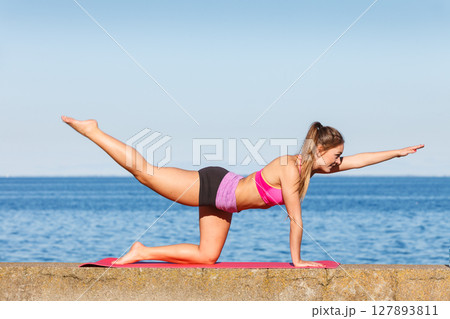 Woman doing sports exercises outdoors by seaside 127893811