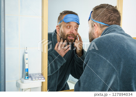 Sleepy man looking at mirror 127894034
