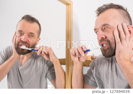 Bored guy brushing his teeth in bathroom 127894039