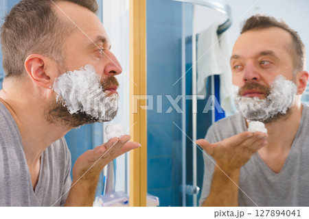 Guy shaving his beard in bathroom Guy shaving his beard in bathroom 127894041