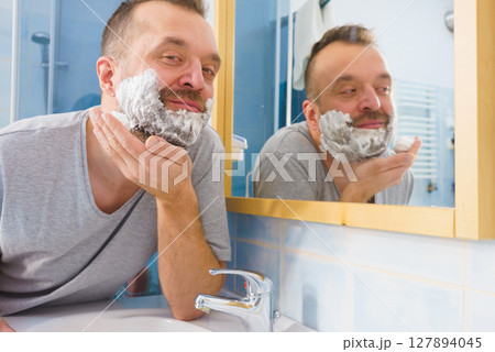 Guy shaving his beard in bathroom Guy shaving his beard in bathroom 127894045