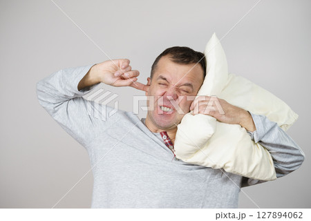 Sleepy man with pillow closing his ear Sleepy man with pillow closing his ear 127894062
