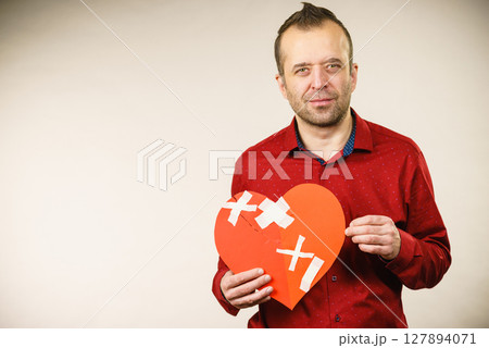 Adult man holding broken heart Adult man holding broken heart 127894071