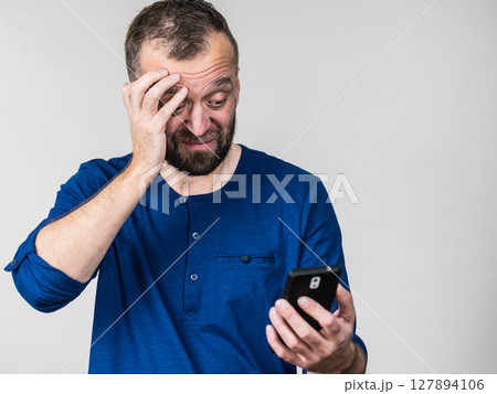 Worried adult man looking at smartphone 127894106