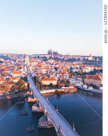 A breathtaking aerial view captures the medieval city of Prague at sunrise. The warm light highlights the Charles Bridge, Vltava River, and historic architecture, creating a serene morning atmosphere. A breathtaking aerial view captures the medieval city of Prague at sunrise. The warm light highlights the Charles Bridge, Vltava River, and historic architecture, creating a serene morning atmosphere. 127894160