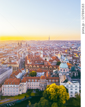 A breathtaking aerial perspective of Old Town Prague during sunrise showcases the vibrant rooftops and historic architecture. 127894163