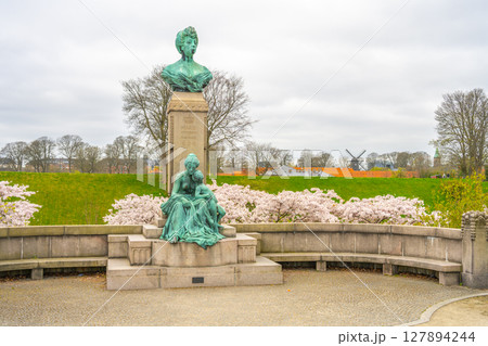 The statue of Princess Marie stands gracefully at Kastellet, surrounded by lush greenery and blooming cherry blossoms. The tranquil setting enhances the statue's beauty on a cloudy day. 127894244