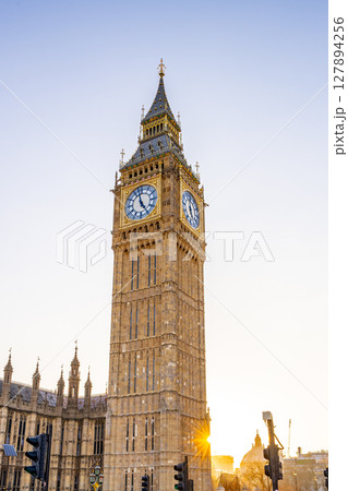 Big Ben towers over the London skyline, basking in soft golden sunlight during early evening. The iconic clock is surrounded by architectural beauty and vibrant city life. Big Ben towers over the London skyline, basking in soft golden sunlight during early evening. The iconic clock is surrounded by architectural beauty and vibrant city life. 127894256